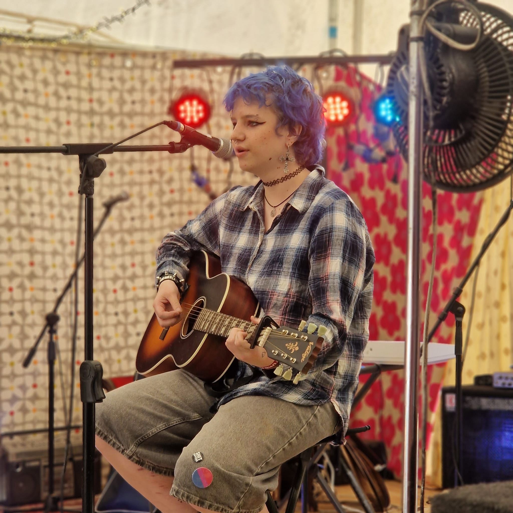Maeve performing with guitar at Forest Fest